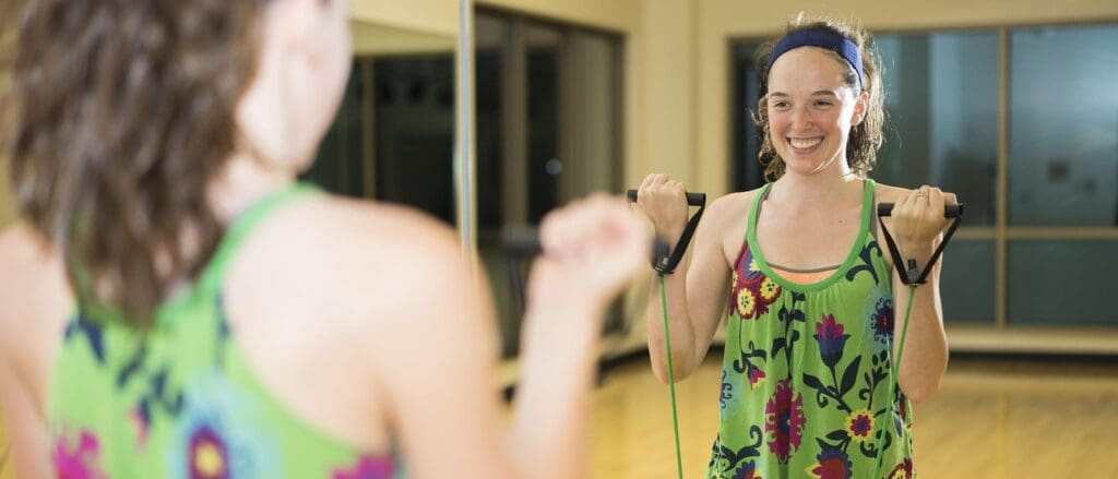 Picture of a woman using resistance bands. exercises over age 50 for cardio health, strong muscles, and healthy aging. Walking, Tai Chi, Weight Training, Chair Squats