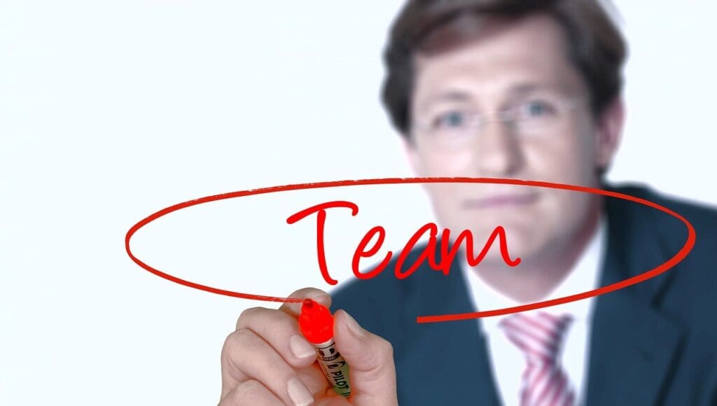 Picture of a man writing the word Team. What is Extrinsic Motivation, skill development, increase productivity