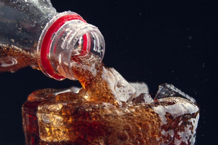 Picture of a cola soda being poured. Dangers of drinking soda.