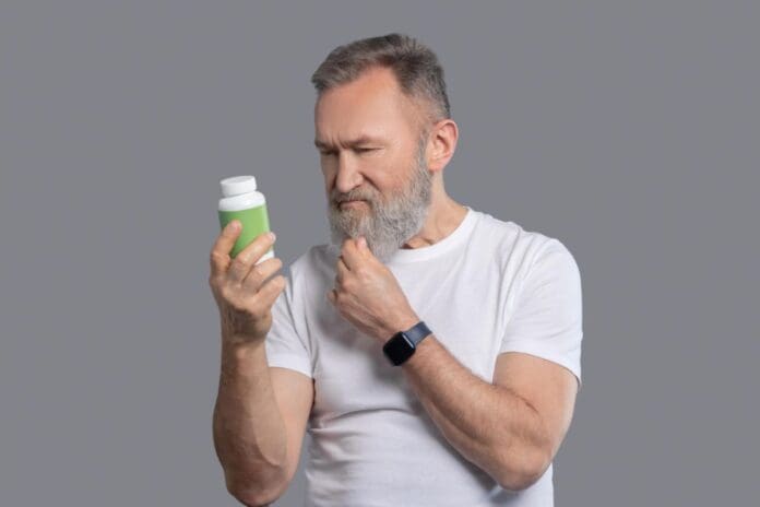 Man looking at a supplement label. Best Supplements for Men Over 60 to Build Muscle